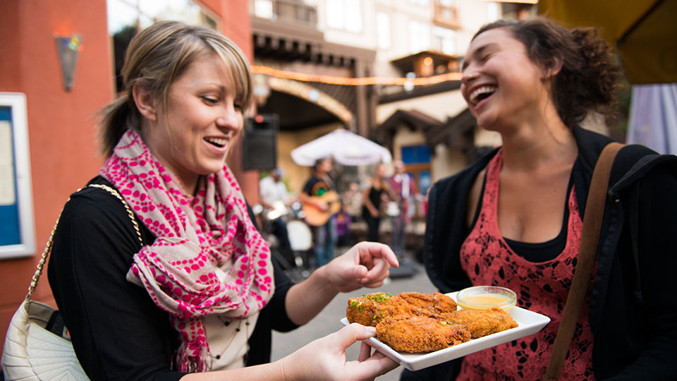 A woman with a plate of chicken at Guitar Strings vs Chicken Wings in The Village at Palisades Tahoe.