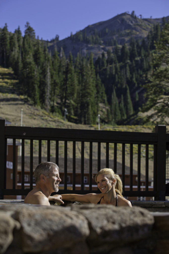 Couple smiling in a hot tub at The Village at Squaw Valley in summer