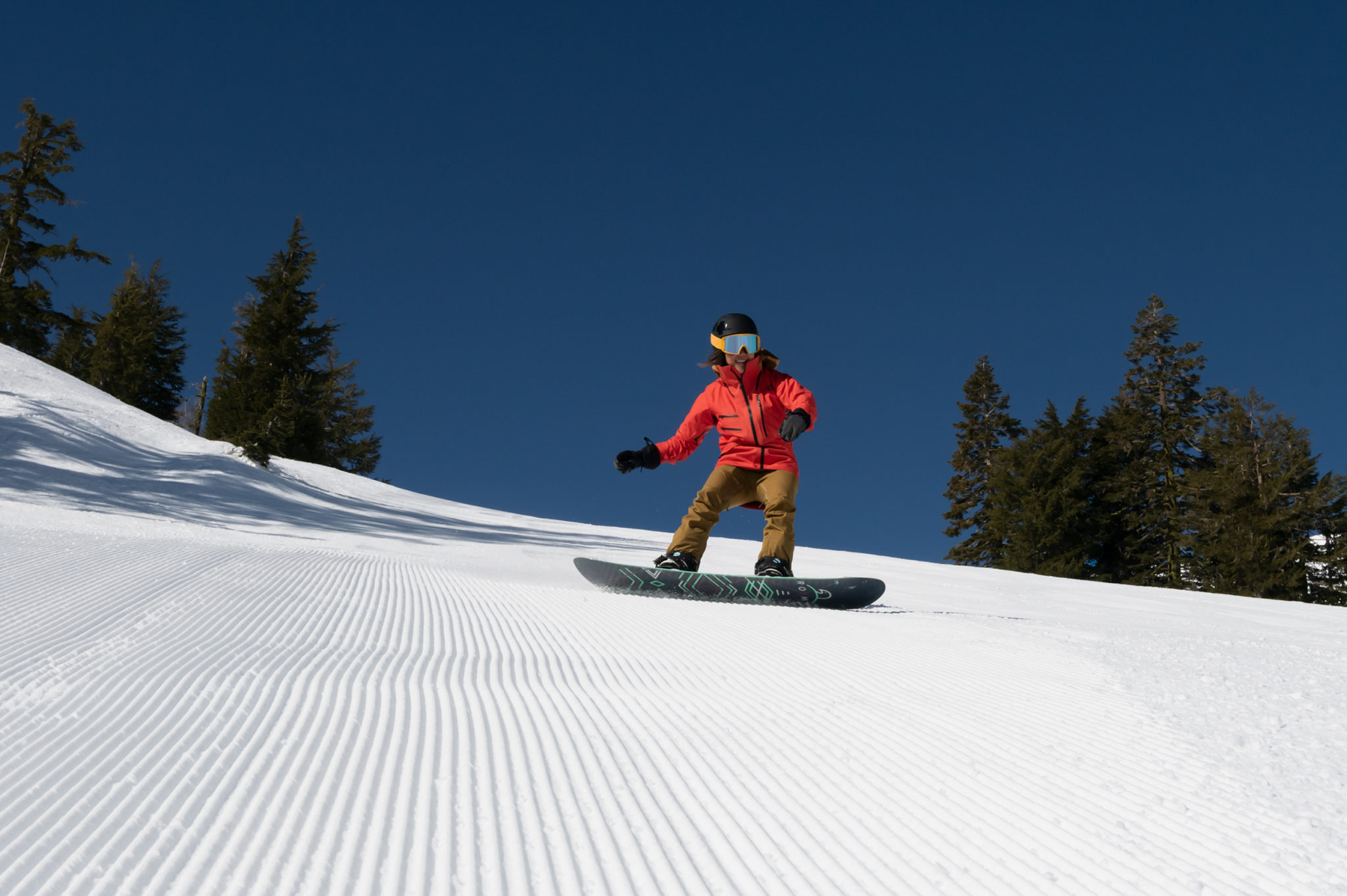 Female snowboarder riding on corduroy at Alpine Meadows on a spring day