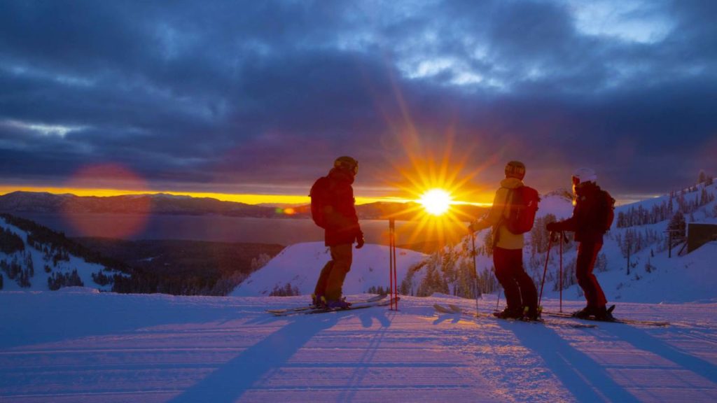Three people watch the sunrise over the Lake as part of a special early-up program at Palisades Tahoe. 