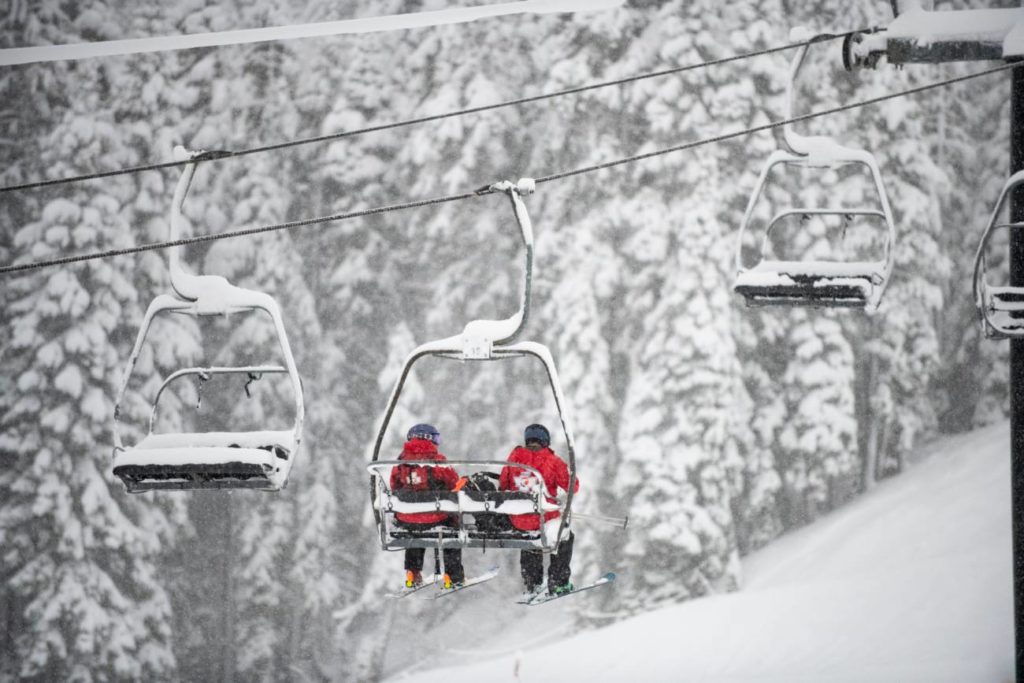 Patrollers ride up a lift to perform avalanche control work.