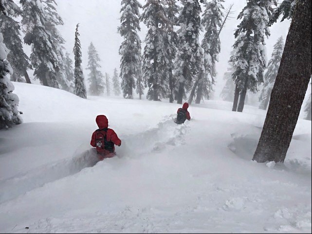 Two patrollers wade through wasit-deep snow at Palisades Tahoe