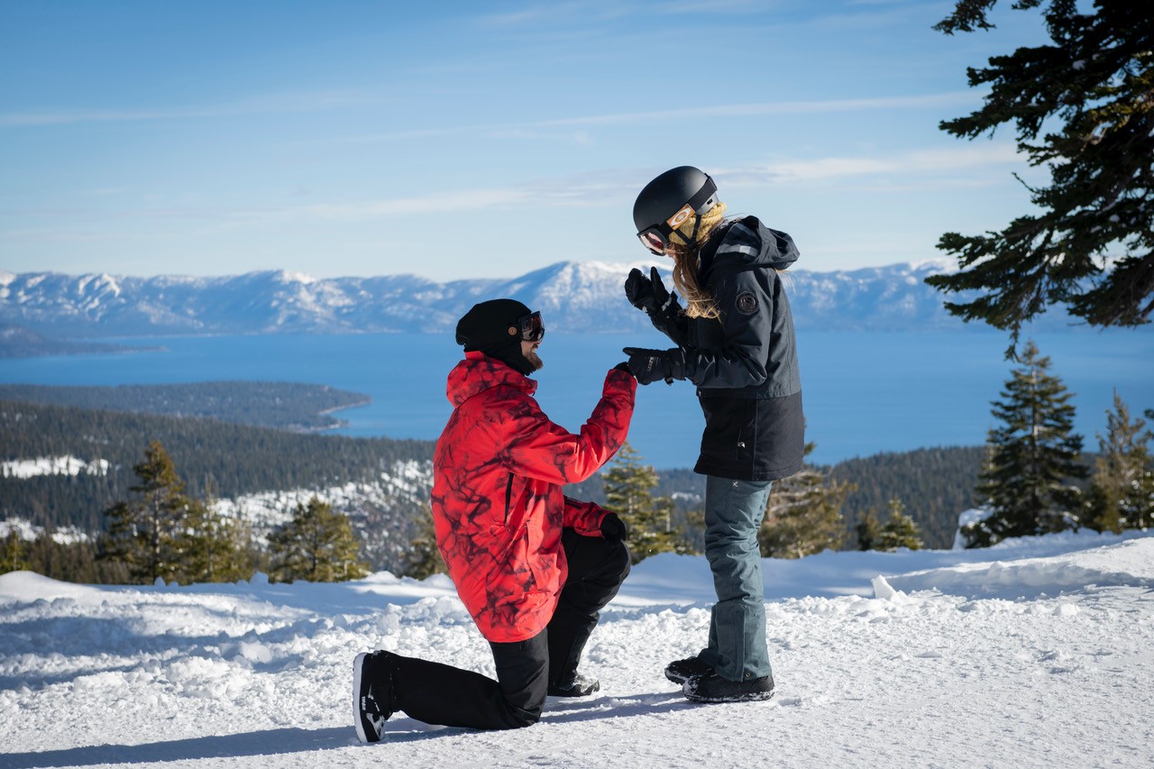 Couple getting engaged during winter at Palisades Tahoe with Lake Tahoe in the background