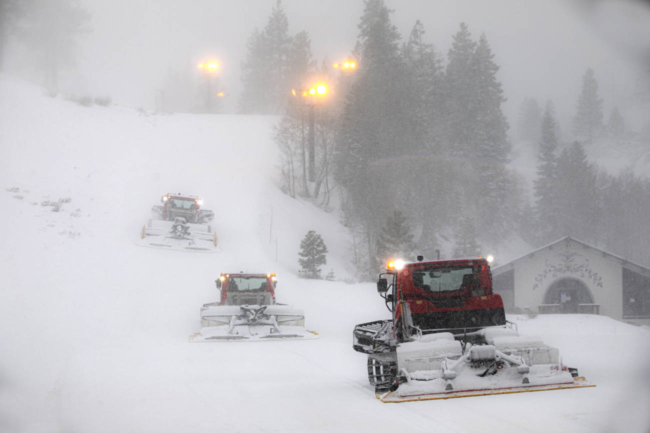 Three snowcats travel uphill in an April storm at Palisades Tahoe.