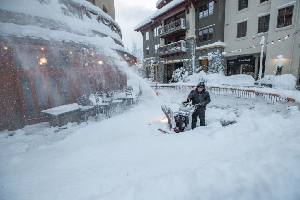 An employee uses a snowblower to remove snow in The Village at Palisades Tahoe.