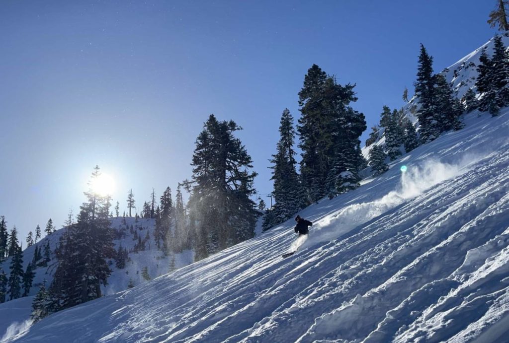 Skier in powder with bluebird sunshine