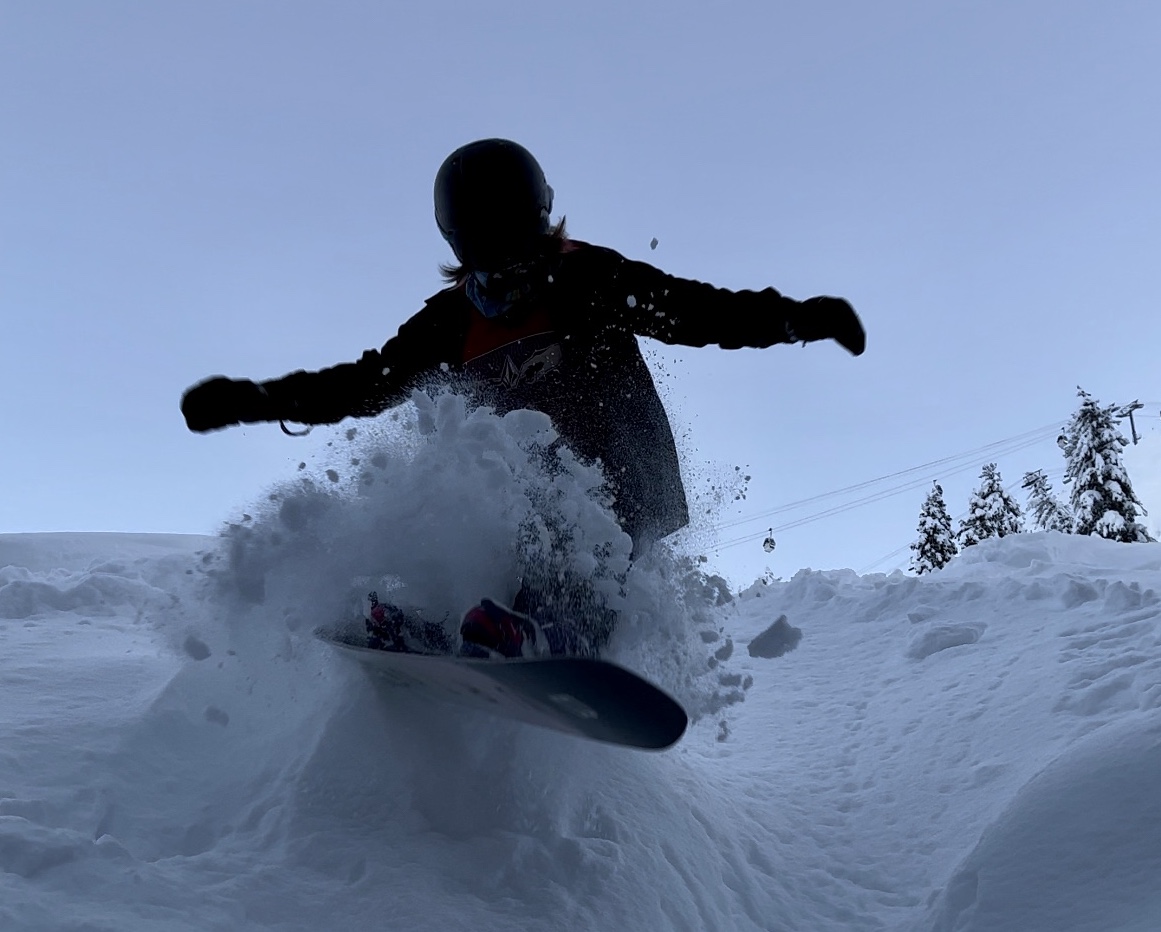 snowboarder in deep powder below the new base to base gondola