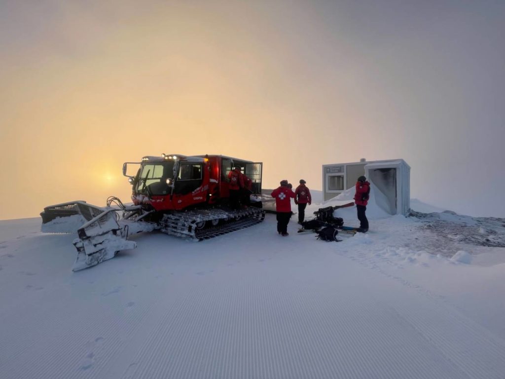 Patrollers in front of a Patrol shack and snowcat at Palisades.
