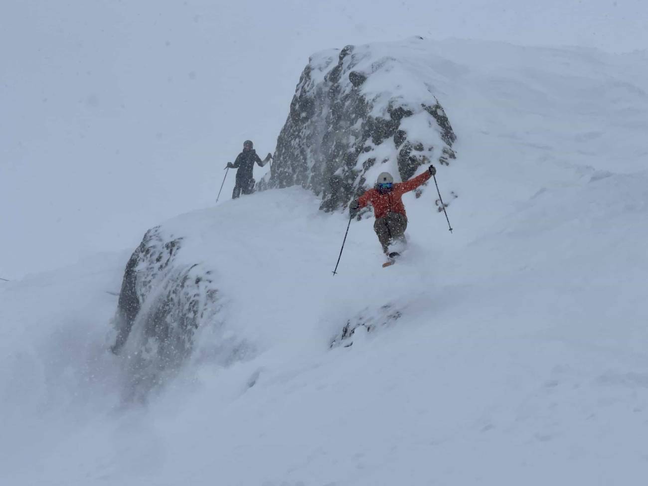 skier getting air off snowy rock