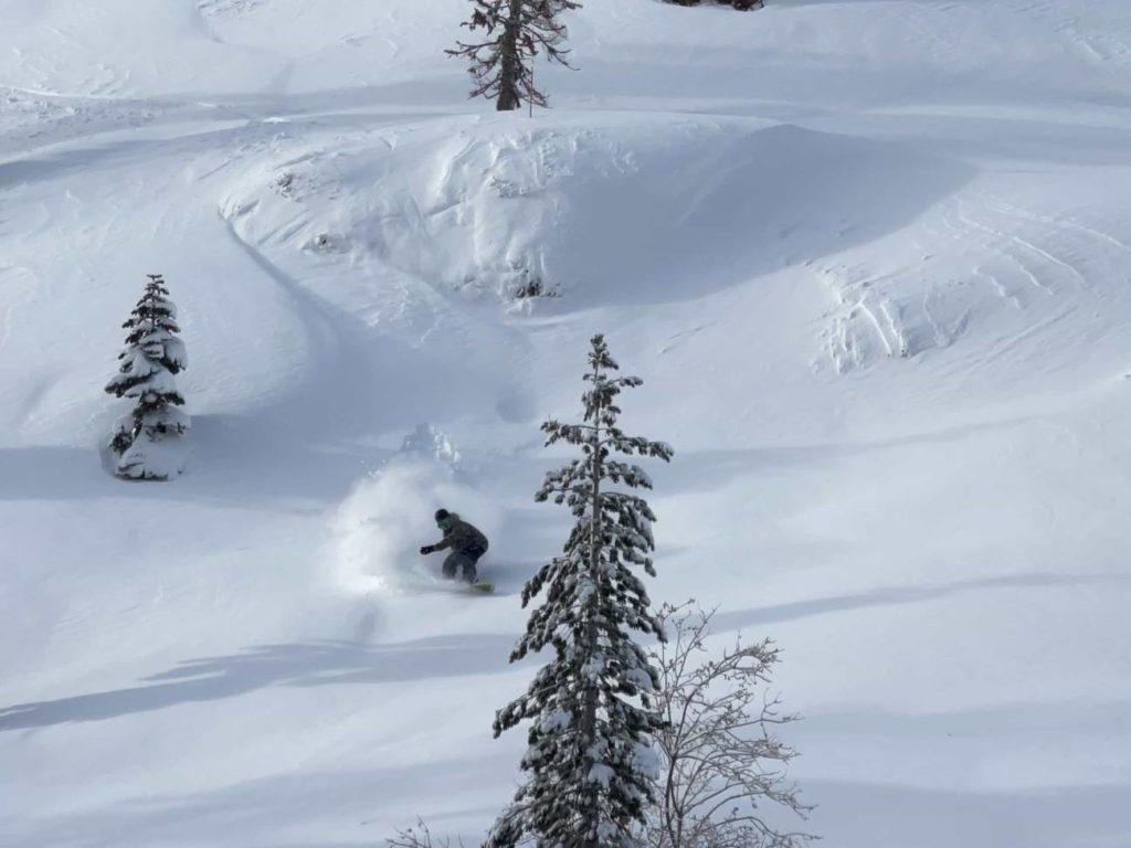 skier gets air off rock in deep snow