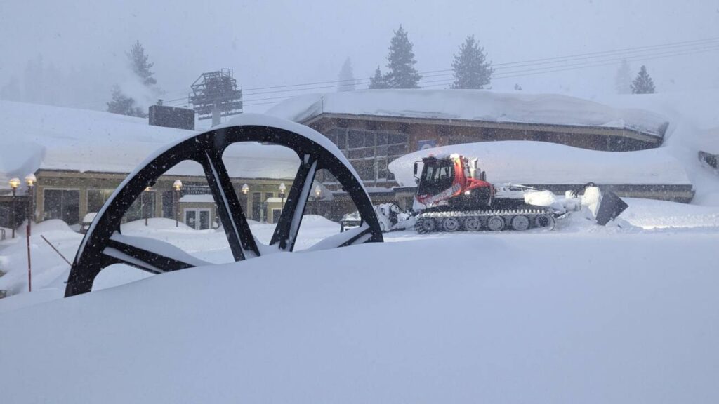 A snowcat in front of Le Chamois during a blizzard.