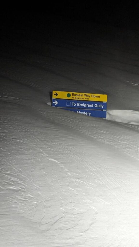 Directional signage on the upper mountain buried in snow.