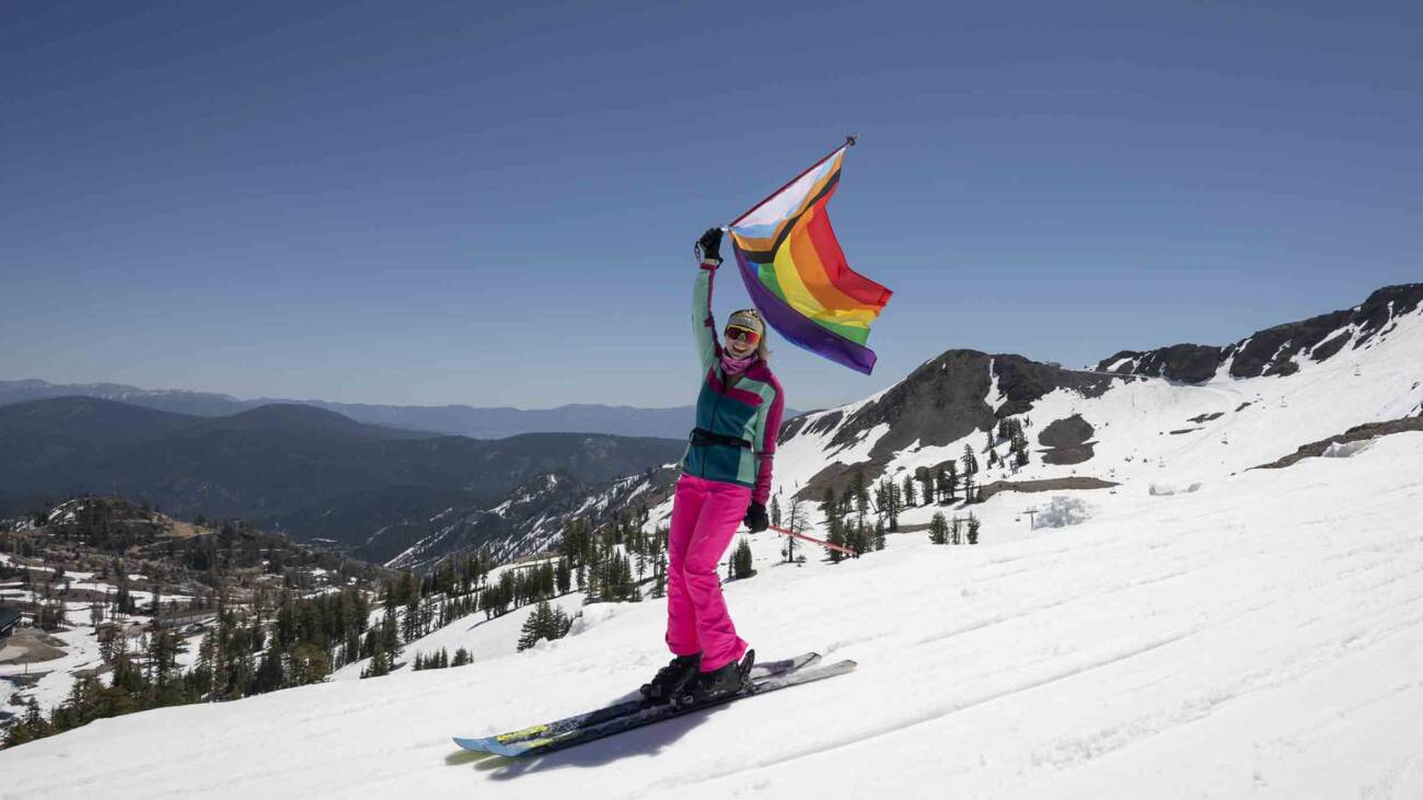 A skier carrying a Pride flag at Palisades Tahoe.