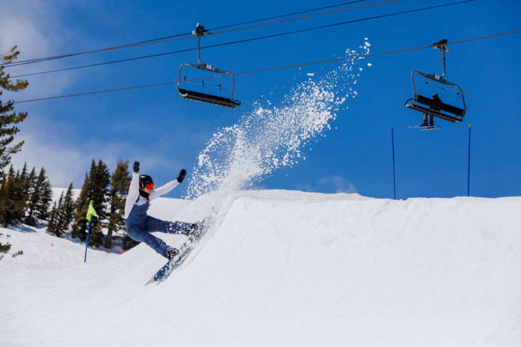 A snowboarder attempts an impressive trick on the park terrain at Palisades Tahoe in the spring.