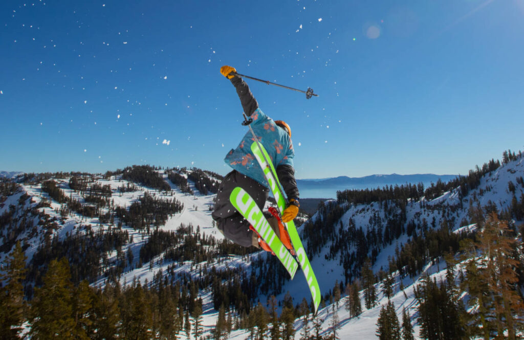 A skier drops into all-time spring skiing conditions, launching off beautiful granite peaks at Palisades Tahoe.