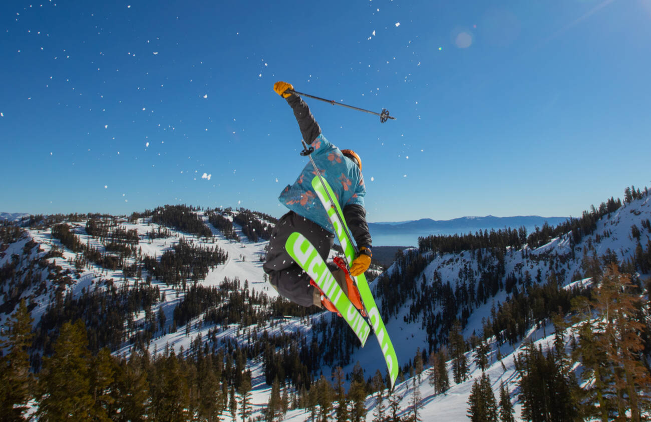 A skier drops into all-time spring skiing conditions, launching off beautiful granite peaks at Palisades Tahoe.