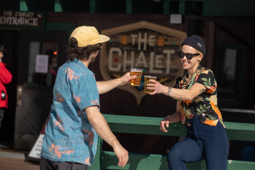 Two friends enjoy a beverage at the Alpine Chalet at Palisades Tahoe.