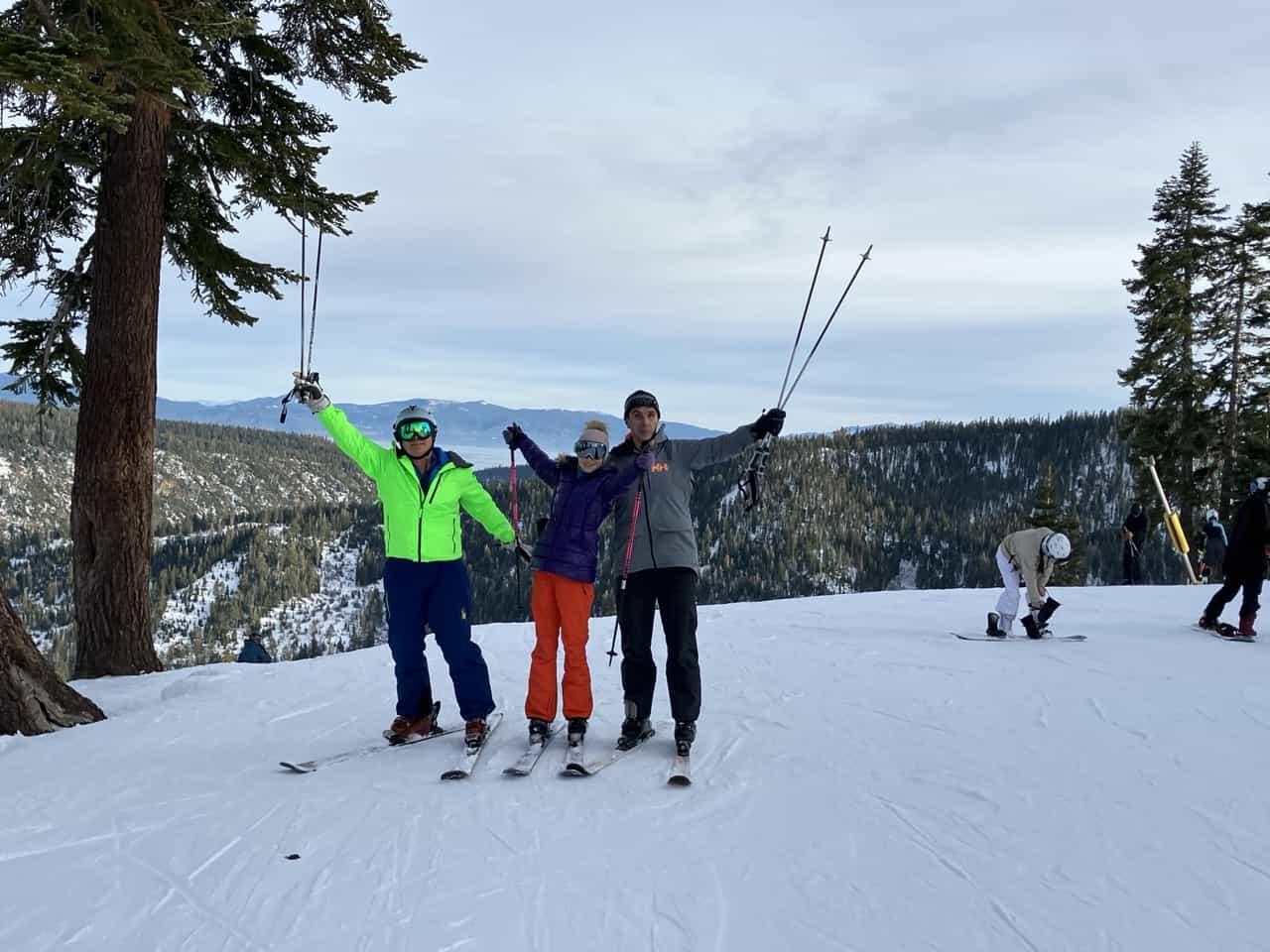 3 skiers celebrate at top of snowy mountain