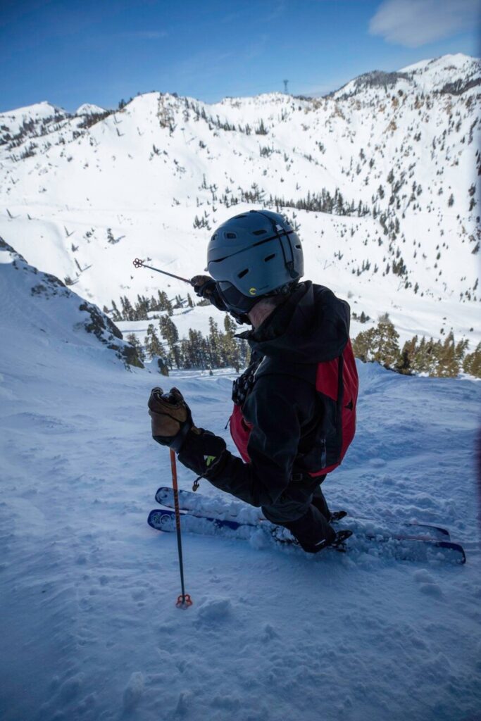 A photo of Gael Williams, a ski patroller, standing above steep terrain.