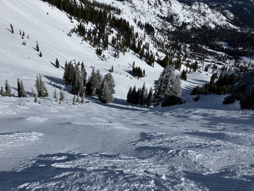 Looking down snowy mogul ski slope