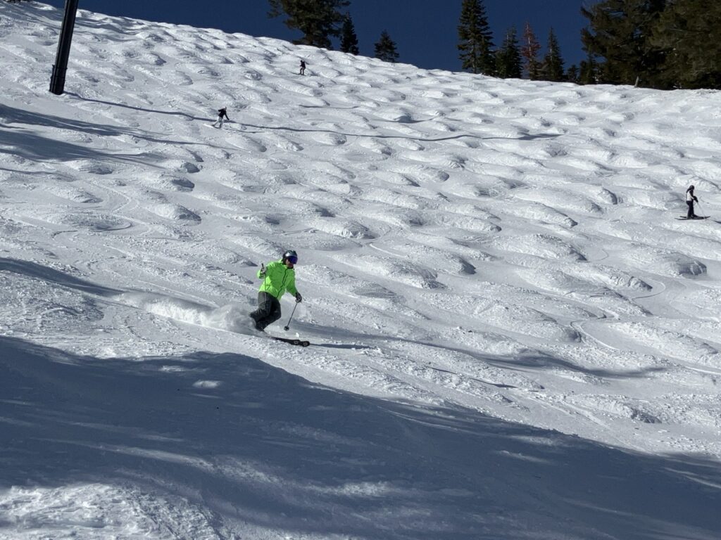 Skier on bumpy snowy slope.