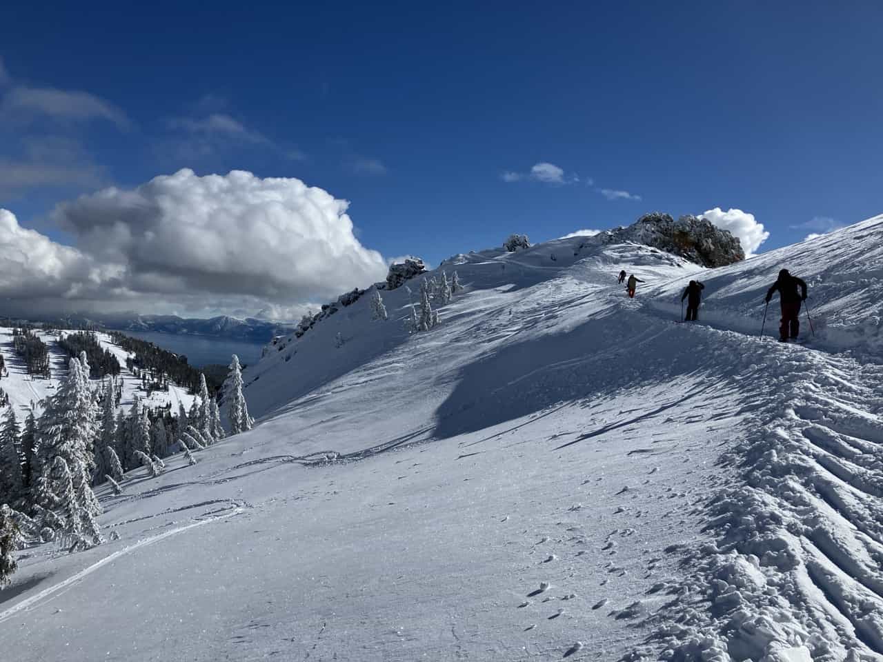 skiers traversing across top of snowy slope