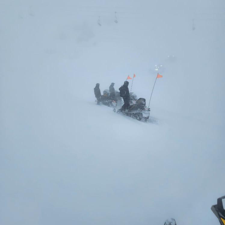 Lift Maintenance technicians on their snowmobiles in the wind.