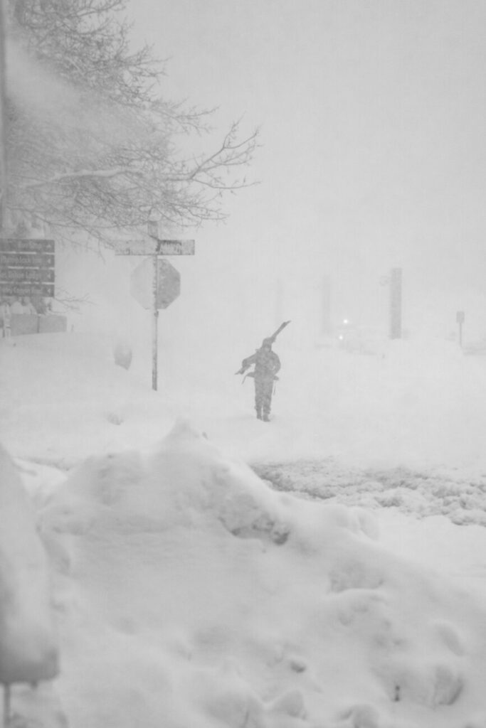 Person carrying their skis through low visibility.