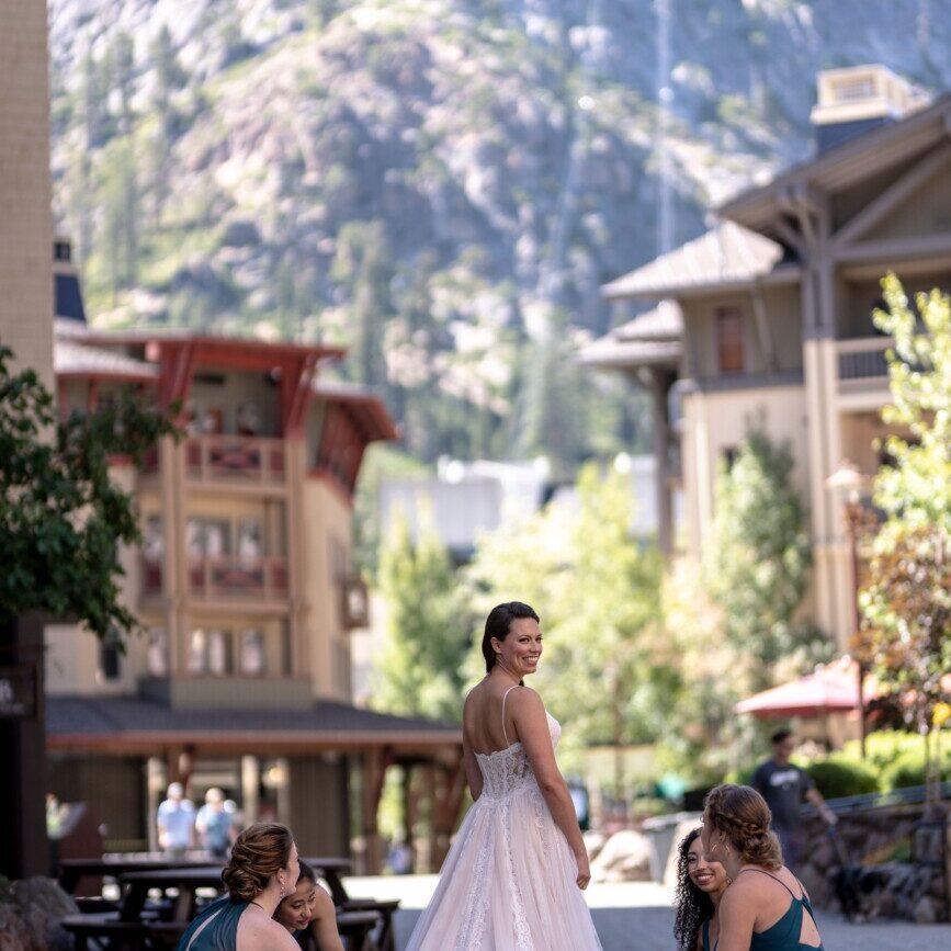 Bride stands in The Village at Palisades Tahoe during a sunny day while wearing a stunning wedding dress. 