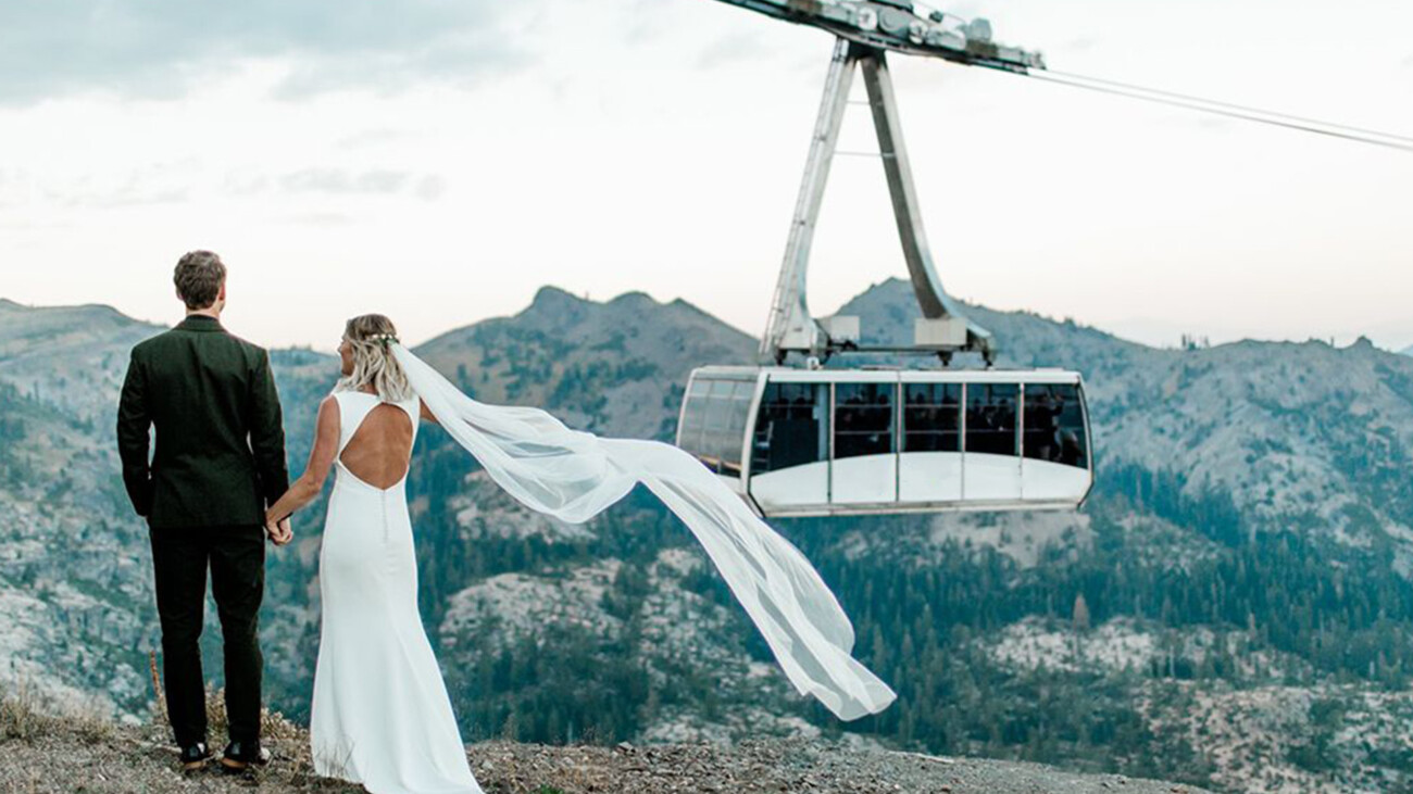 Bride and groom look out over Olympic Valley and Palisades Tahoe with the Palisades Tahoe Aerial Tram in the background.