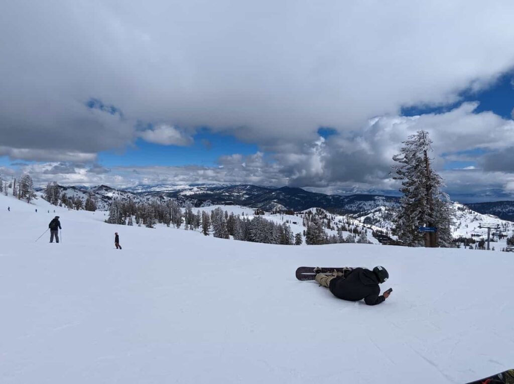 snowy ski slopes with snowboarder laying on floor