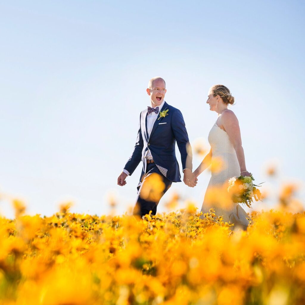 Bride and groom walk in a wildflower meadow at Palisades Tahoe in Olympic Valley, California. 