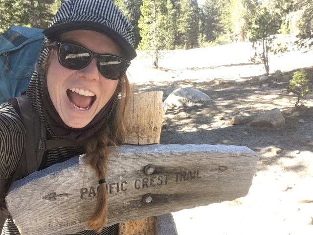 Kate taking a selfie in front of a sign on the Pacific Crest Trails.