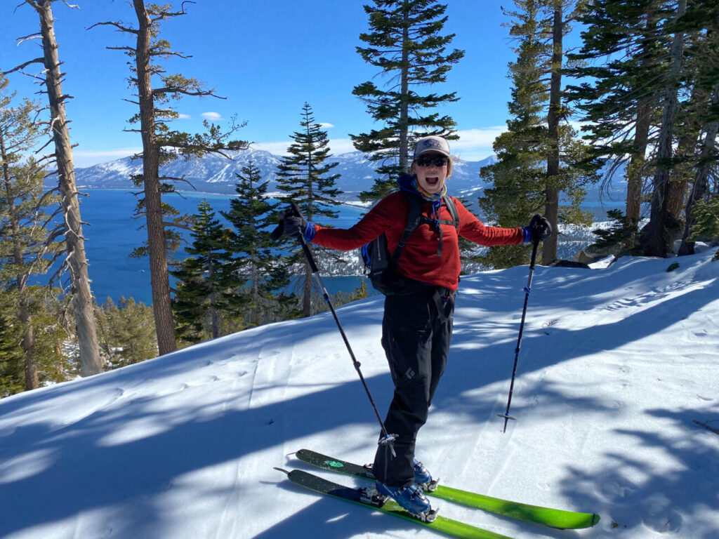 Kate poses while backcountry skiing in front of a view of Lake Tahoe on the trail for Jake's Peak during spring. 