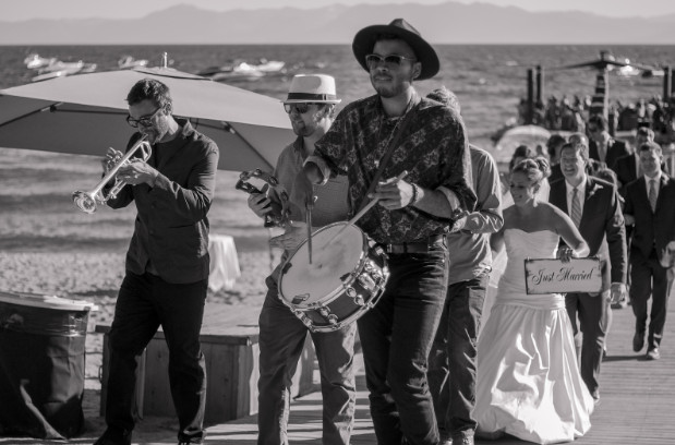 A newly married couple and their wedding party follows a band back to shore from scenic dock located on Lake Tahoe.