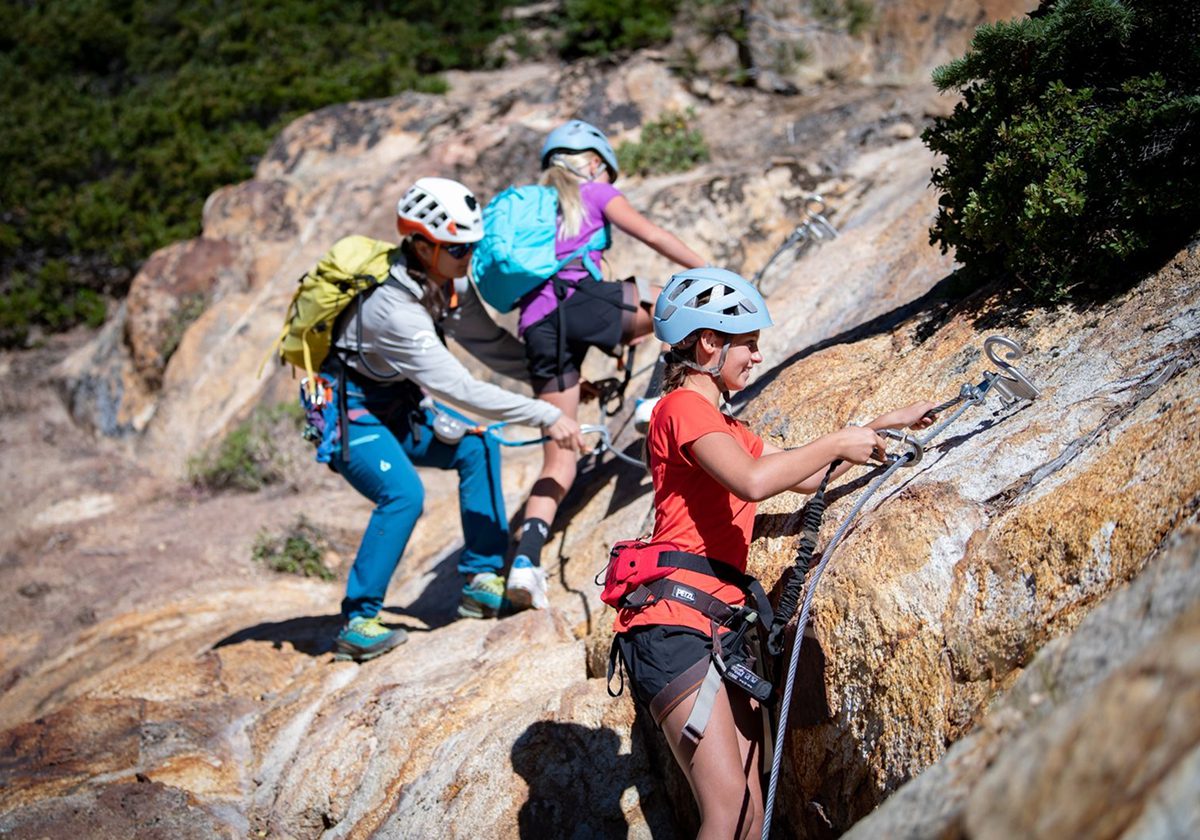 Three people in a family climbing the Via Ferrata