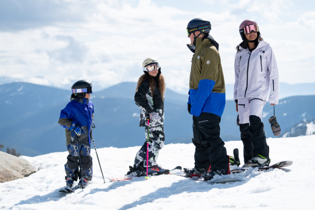 Family of skiers and snowboarders on-mountain, getting ready to ride at Palisades Tahoe