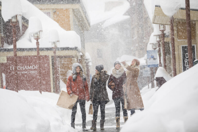 Group walking through The Village at Palisades Tahoe on a snowy day