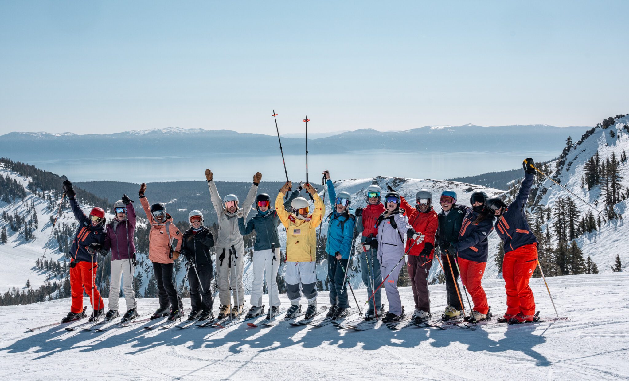Group of participants smiling at camera with backdrop of Lake Tahoe during Amie Engerbretson 2025 camp
