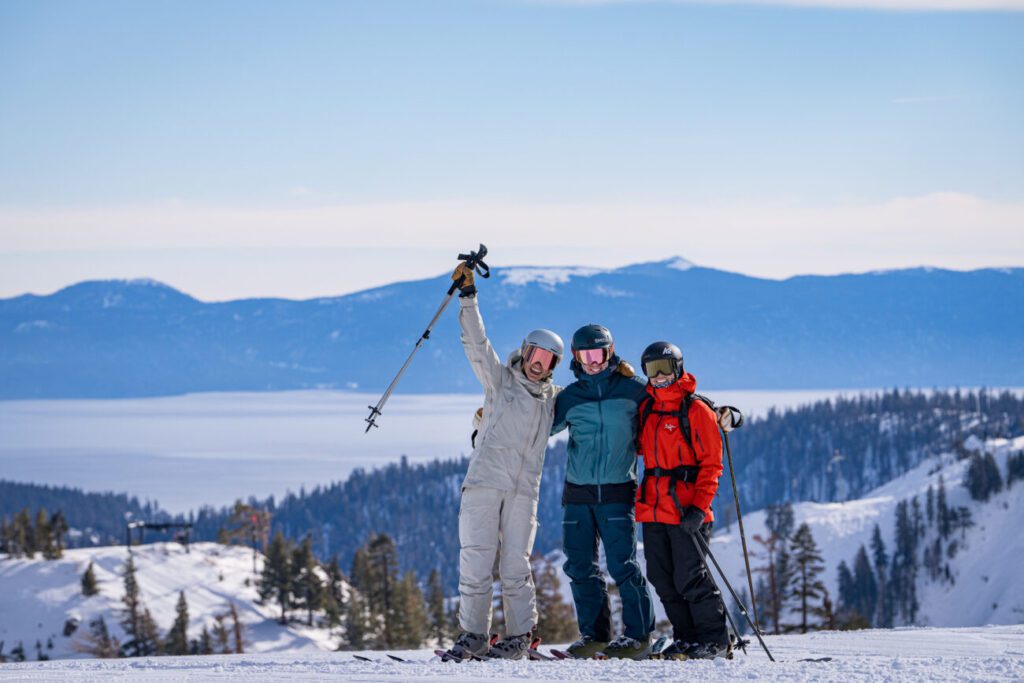 Skiers smiling for a picture with Lake Tahoe in the background