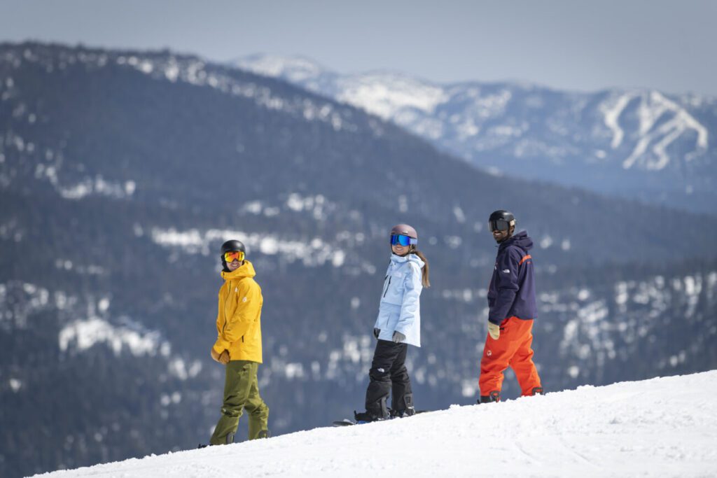 Instructor and two snowboarders smiling for a picture