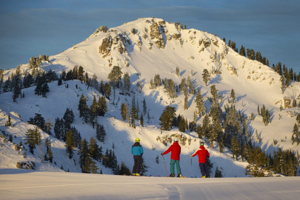 Three skiers looking at Granite Chief in the distance