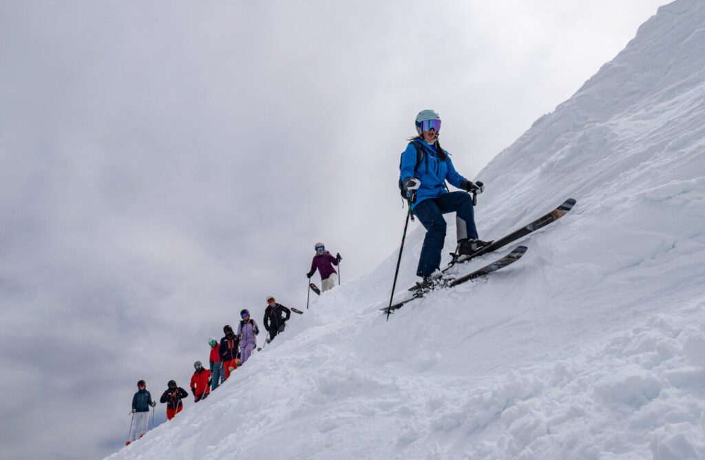 Group of gals during the Women of Winter Clinic watching one skier prepare to drop in